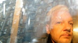 FILE: Buildings are reflected in the window as WikiLeaks founder Julian Assange is taken from court, where he appeared on charges of jumping British bail seven years ago, in London, May 1, 2019.