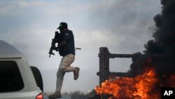 FILE - A police officer abandons his vehicle during a demonstration that turned violent in which protesters demanded justice for the assassinated President Jovenel Moise in Cap-Haitien, Haiti, July 22, 2021.