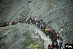 Hindu pilgrims travel by horseback and by foot, beside a glacier-fed stream during their annual pilgrimage to holy cave in India. (Photo by Wasim Nabi)