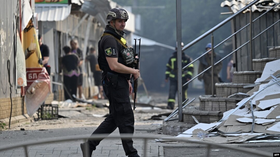 A Ukrainian policeman patrols in front of destroyed shops on a local market after a rocket attack in the town of Sloviansk, July 3, 2022.