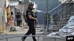 A Ukrainian policeman patrols in front of destroyed shops on a local market after a rocket attack in the town of Sloviansk, July 3, 2022.