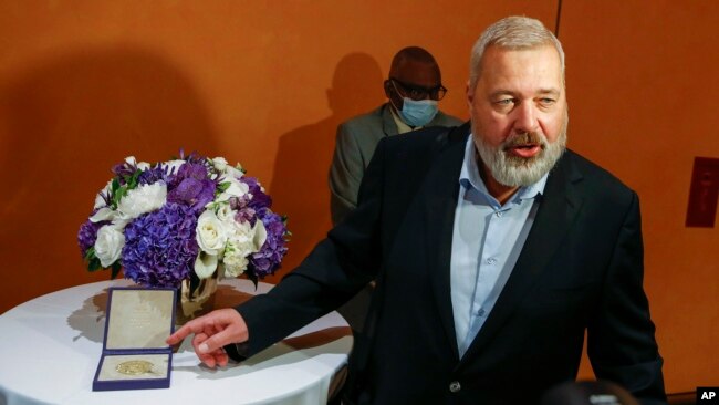 Nobel Peace Prize winner Dmitry Muratov, editor-in-chief of the influential Russian newspaper Novaya Gazeta, poses for a picture next to his 23-karat gold medal before it is auctioned at the Times Center, Monday, June 20, 2022, in New York. (AP Photo/Edua