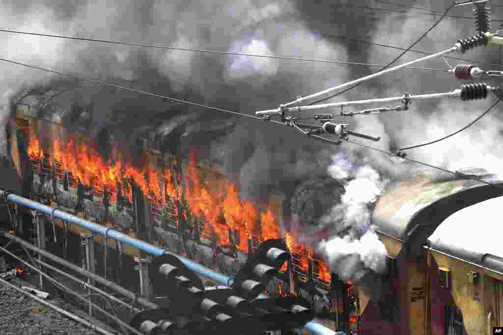 Flames rise from a train set on fire by protesters at Secundrabad railroad station in Hyderabad, India.