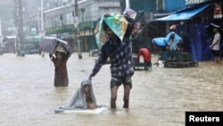 People wade through the water as they look for shelter during a flood, amidst heavy rains that caused widespread flooding in the northeastern part of the country, in Sylhet, Bangladesh, June 18, 2022.