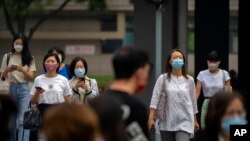 Commuters wearing face masks wait to cross an intersection in the central business district in Beijing, June 17, 2022. 