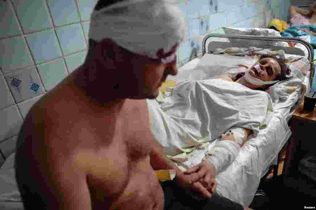 Sepasang kekasih yang terluka di pusat perbelanjaan akibat terkena serangan rudal Rusia, tampak berpegangan tangan saat dirawat di sebuah rumah sakit di kota Kremenchuk, Ukraina (27/6). (Foto: Reuters)&nbsp;