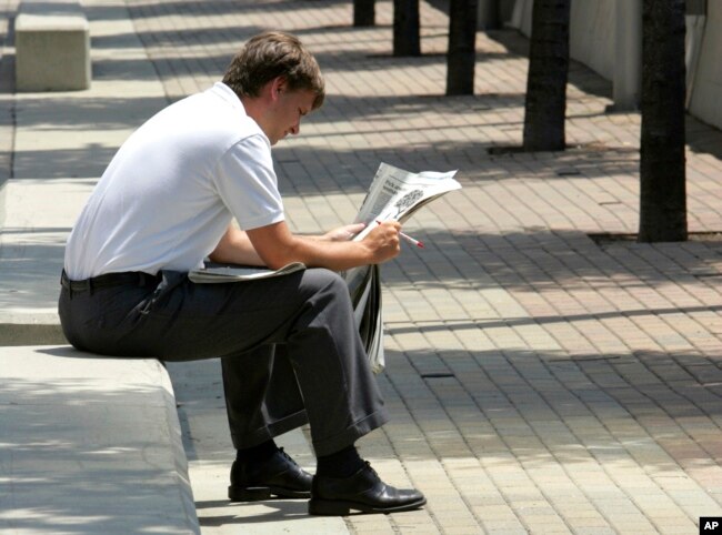 FILE - A man reads a newspaper during his lunch break in Cincinnati on July 6, 2005. A report from Northwestern University says local newspapers in the United States are dying at the rate of two per week.