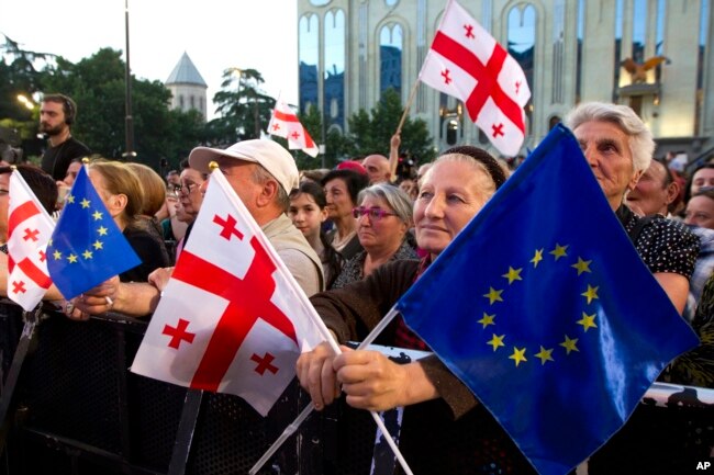 FILE - Demonstrators gather with Georgian national and EU flags in front of the parliament building in Tbilisi, Georgia, July 3, 2022.