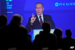 Participants watch as Russian President Vladimir Putin addresses a plenary session of the St. Petersburg International Economic Forum in St. Petersburg, June 17, 2022.