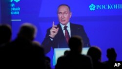 Participants watch as Russian President Vladimir Putin addresses a plenary session of the St. Petersburg International Economic Forum in St. Petersburg, June 17, 2022. 
