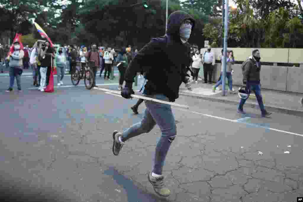 Un manifestante corre hacia la policía frente a la Unidad de Flagrancia de la Fiscalía durante una protesta exigiendo la libertad del líder indígena Leonidas Iza, en Quito. Ecuador, el martes 14 de junio de 2022. (Foto AP/Dolores Ochoa)