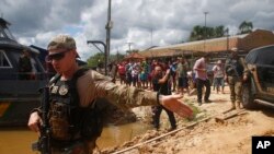 A federal police officer stands guard as a suspect is transported to the area where Indigenous expert Bruno Pereira and freelance British journalist Dom Phillips disappeared, in Atalaia do Norte, Amazonas state, Brazil, June 15, 2022.