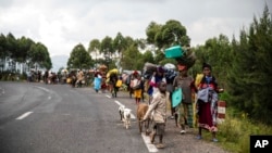 FILE - People walk on the road near Kibumba, north of Goma, Democratic Republic of the Congo, as they flee fighting between Congolese forces and M23 rebels in North Kivu, May 24, 2022.