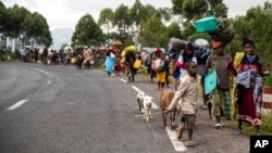 FILE - People walk on the road near Kibumba, north of Goma, Democratic Republic of the Congo, as they flee fighting between Congolese forces and M23 rebels in North Kivu, May 24, 2022.