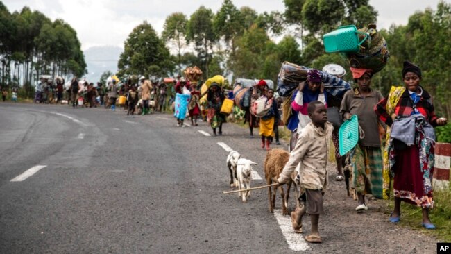 FILE - People walk on the road near Kibumba, north of Goma, Democratic Republic of the Congo, as they flee fighting between Congolese forces and M23 rebels in North Kivu, May 24, 2022.