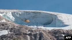 A rescue helicopter flies above the Marmolada glacier, near Canazei, Italy, on July 4, 2022, one day after part of the glacier collapsed, killing seven people.