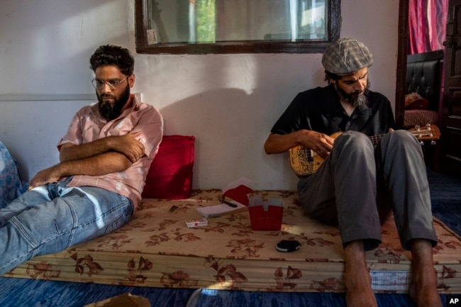 Sarfaraz Javid, a Kashmiri musician and singer plays guitar as Arif Farooq, a rap singer sits nearby in a studio on the outskirts of Srinagar, Indian Kashmir, June 17, 2022. (AP Photo/Dar Yasin)