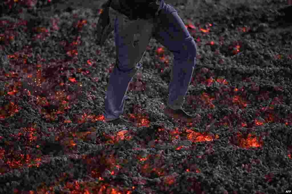 A man walks barefoot across a bed of burning coals during the traditional Sao Joao prayer, performed by the Quilombola community of Mato do Ticao, in Jaboticatubas, Minas Gerais State, Brazil.