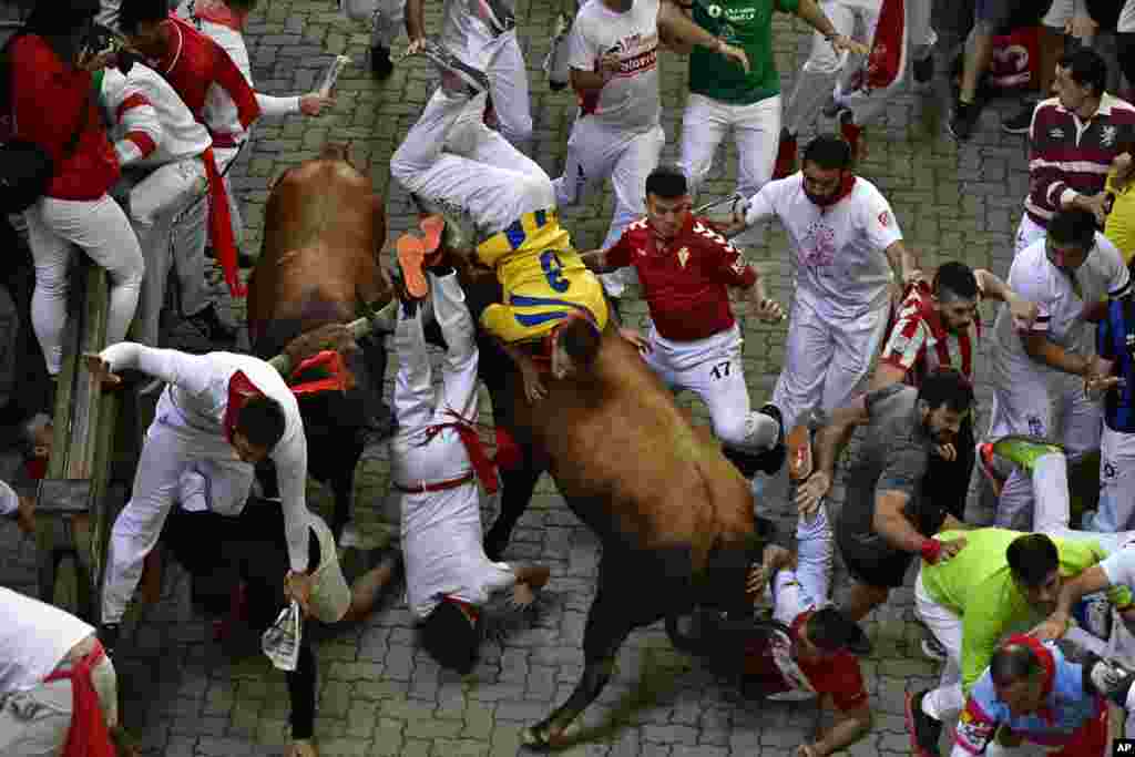Runners fall as another is tossed by a fighting bull during the running of the bulls at the San Fermin Festival in Pamplona, northern Spain.