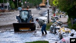 Se ve a los residentes de Red Lodge, Montana, limpiando lodo, agua y escombros de la calle principal de la pequeña ciudad el martes 14 de junio de 2022, después de que las aguas de la inundación atravesaran un área residencial con cientos de casas. (Foto AP/Matthew Brown)