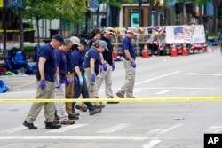 Members of the FBI's evidence response team walk the scene one day after a mass shooting in downtown Highland Park, Illinois, July 5, 2022.