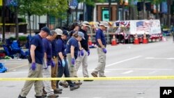 Members of the FBI's evidence response team walk the scene one day after a mass shooting in downtown Highland Park, Ill. July 5, 2022. 