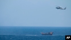 FILE - A U.S. Navy Seahawk helicopter flies over a stateless dhow later found to be carrying a hidden arms shipment in the Arabian Sea, May 6, 2021. 