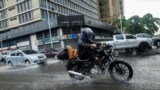 Un hombre levanta los pies mientras conduce una motocicleta para evitar mojarse después de las lluvias causadas por el potencial ciclón tropical dos, en Caracas, Venezuela, el 29 de junio. , 2022. REUTERS/Leonardo Fernández Viloria