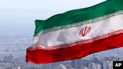 FILE - Iran's national flag waves in Tehran, Iran, March 31, 2020. Iranian media reported a former agriculture minister has been sentenced on corruption charges.