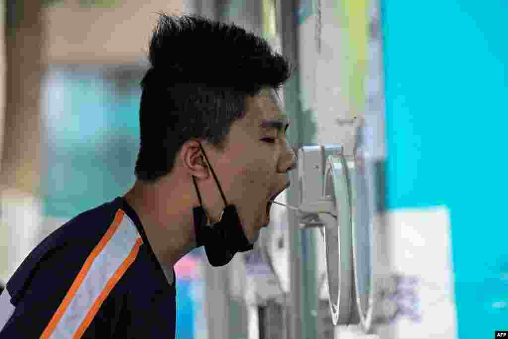 A health worker takes a swab sample from a man to be tested for COVID-19 at a testing station in Beijing, China.