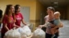 A woman carries her child as she receives humanitarian aid provided by local authorities in Selidovo, Donetsk region, Ukraine, Tuesday, June 14, 2022.