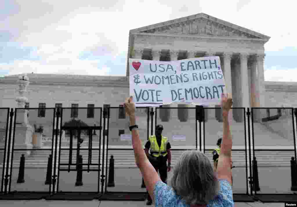 Un manifestante por el derecho al aborto sostiene un cartel frente a la Corte Suprema. El cartel dice: Estados Unidos, la Tierra y los derechos de las mujeres. Vota demócrata.&nbsp;