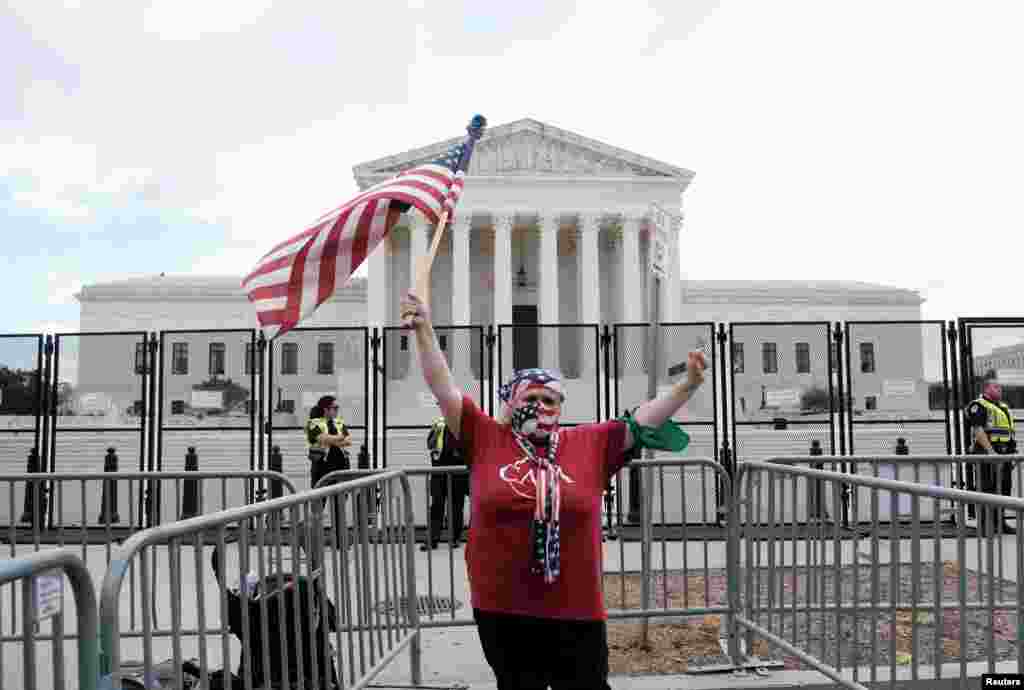 Un manifestante sostiene la bandera nacional de Estados Unidos frente a la Corte Suprema.
