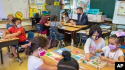 FILE - California Gov. Gavin Newsom sits with students of a second grade classroom at Carl B. Munck Elementary School in Oakland, Calif., on Aug. 11, 2021.