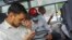 Indian journalist Mohammed Zubair, center, wearing a cap and a face mask, sits in a police vehicle in New Delhi, June 28, 2022.