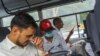 Indian journalist Mohammed Zubair, center, wearing a cap and a face mask, sits in a police vehicle in New Delhi, June 28, 2022.