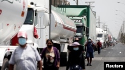 FOTO DE ARCHIVO: Varias personas caminan junto a camiones estacionados durante una huelga nacional de transporte contra los precios del combustible, en Lima, Perú, el 18 de marzo de 2021. REUTERS/Angela Ponce/Foto de archivo