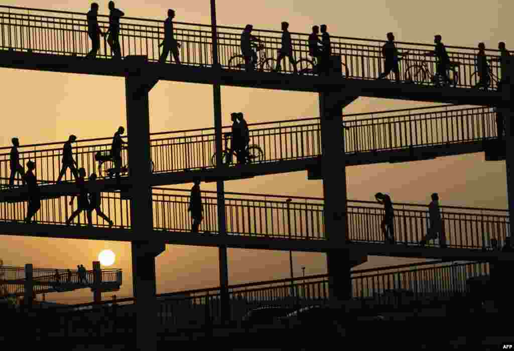 People cross an overhead bridge amid soaring humidity and temperatures in the Gulf emirate of Dubai.