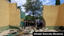 FILE - People stand outside the main prison door that was destroyed during the attack at Kuje Medium prison in Abuja, Nigeria July 6, 2022. 