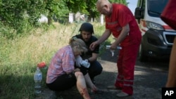 A police officer and paramedic give the first aid to a woman wounded by the Russian shelling in city center in Slavyansk, Donetsk region, Ukraine, Monday, June 27, 2022. (AP Photo/Efrem Lukatsky)