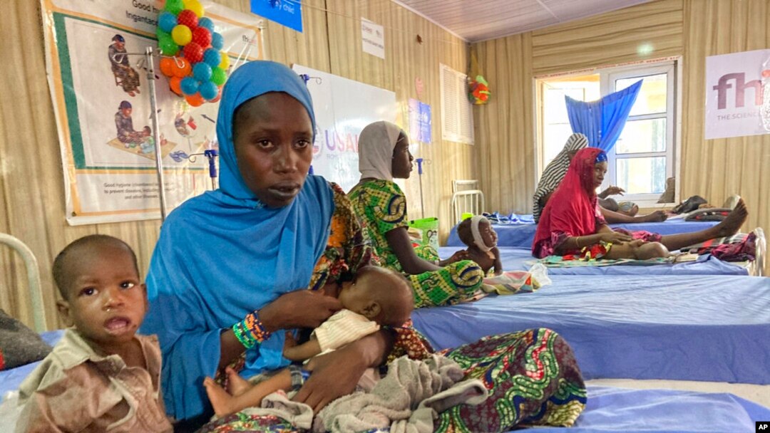 FILE - A woman attends to her malnourished child at the United Nations Nutrition Center in Banki, on the outskirts of Maiduguri, Nigeria, May 3, 2022. 