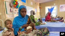FILE - A woman attends to her malnourished child at the United Nations Nutrition Center in Banki, on the outskirts of Maiduguri, Nigeria, May 3, 2022. 
