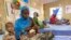 FILE - A woman attends to her malnourished child at the United Nations Nutrition Center in Banki, on the outskirts of Maiduguri, Nigeria, May 3, 2022. 