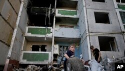 Niños se paran frente a un edificio destruido por los ataques en Chernihiv, Ucrania, el domingo 19 de junio de 2022.
