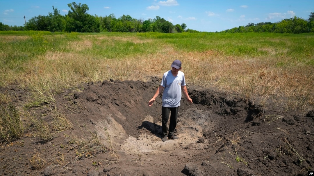 Farmer Serhiy, a local grain producer, shows a crater left by a Russian shell on his field in the village of Ptyche in Ukraine's eastern Donetsk region, June 12, 2022.