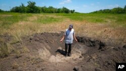 Farmer Serhiy, a local grain producer, shows a crater left by a Russian shell on his field in the village of Ptyche in Ukraine's eastern Donetsk region, June 12, 2022.