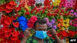 A vendor selling artificial flowers wear face masks distributed by health workers as a safety protocol to curb the spread of COVID-19 coronavirus in Kolkata on July 4, 2022.