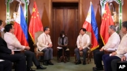 Philippine President Ferdinand Marcos Jr., center, talks with Chinese Foreign Minister Wang Yi during a courtesy call at the Malacanang Presidential Palace in Manila, Philippines on July 6, 2022. (Malacanang Presidential Photographers Division via AP)