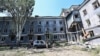 Civilians and Ukrainian servicemen walk in the rubble of the courtyard between the Hotel Industria and civilian buildings after an air strike in the center of Kramatorsk, on July 7, 2022.