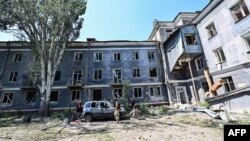 Civilians and Ukrainian servicemen walk in the rubble of the courtyard between the Hotel Industria and civilian buildings after an air strike in the center of Kramatorsk, on July 7, 2022.